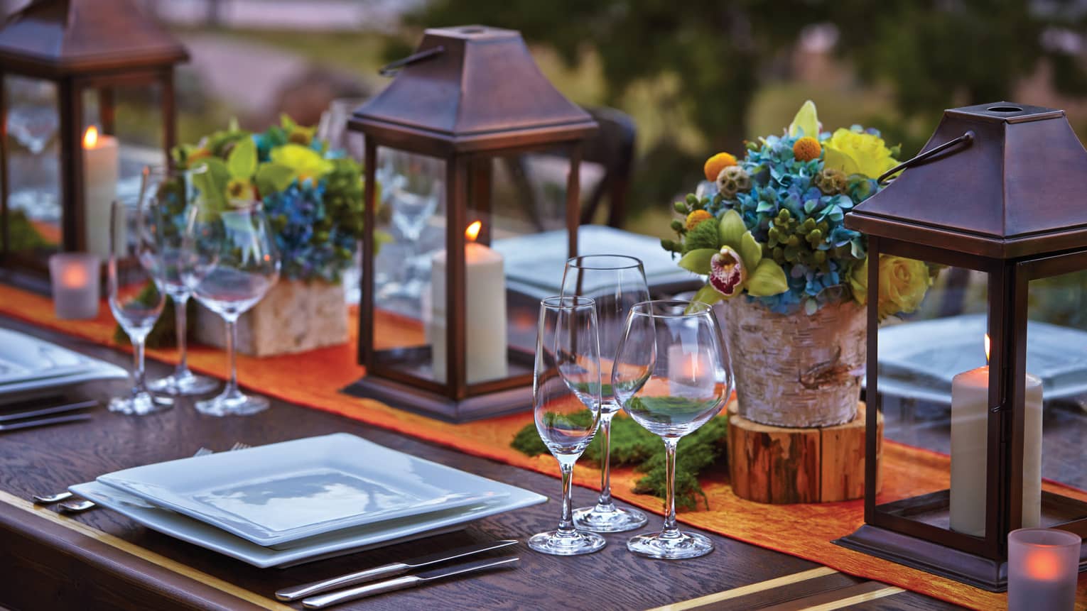 Close-up of lanterns, flowers on patio dining table at sunset