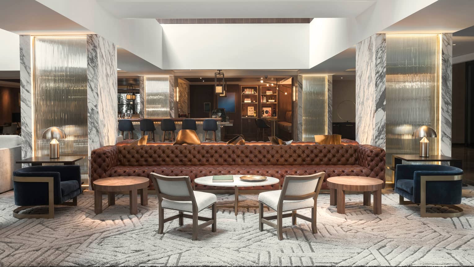 The Meyer Davis lobby with marble pillars, long brown leather sofa, blue velvet chairs and natural lighting