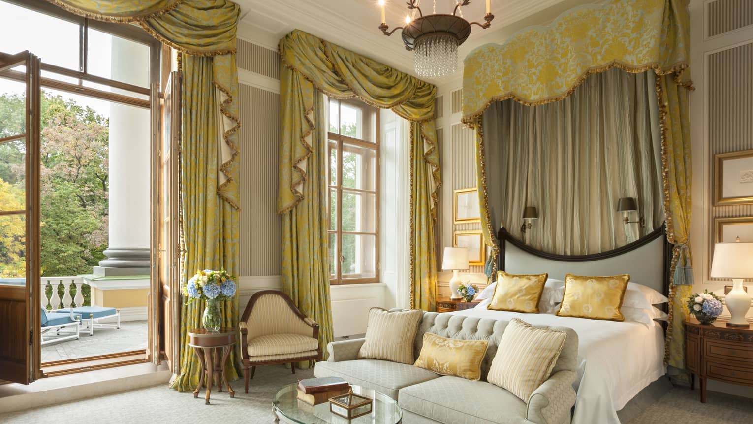 Presidential Suite master bedroom bed with loveseat at foot, gold curtains cascading from high ceilings