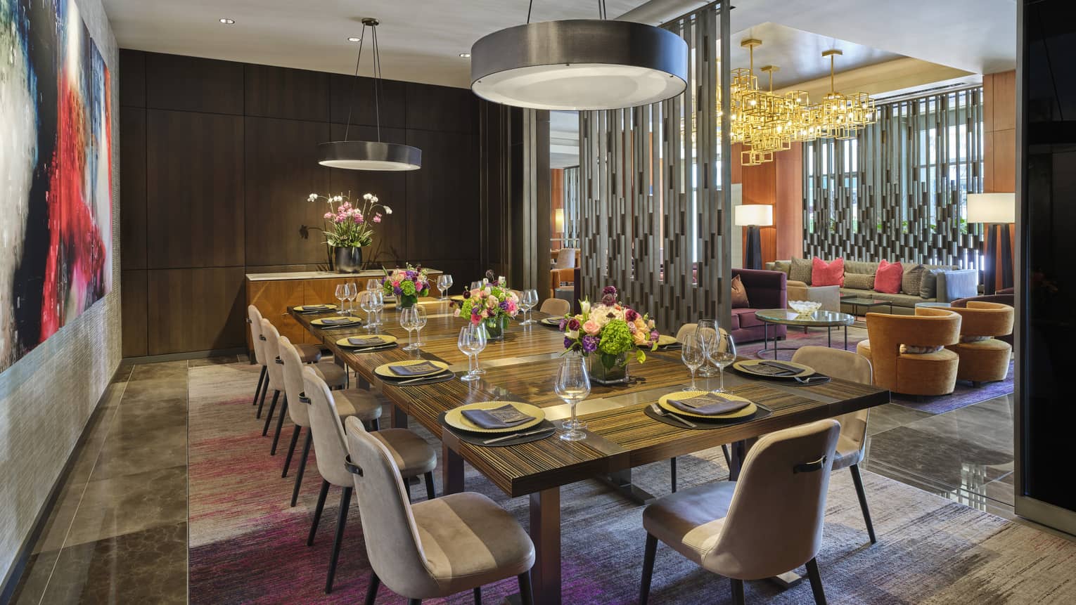 Rectangular table with place settings and flowers, and art on the wall.