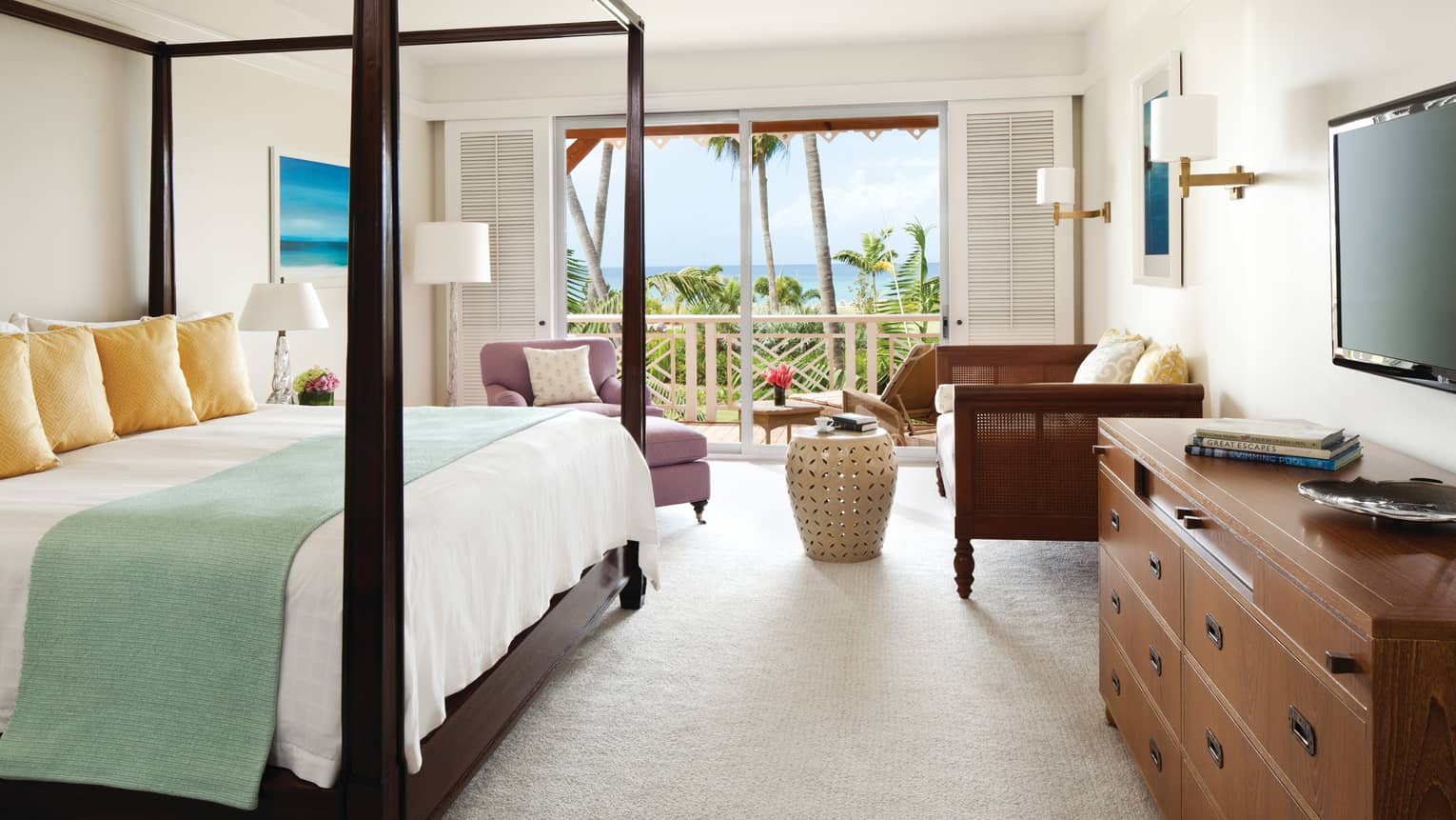 Luxury Suite wood poster bed, blue banket, gold pillows, white carpet, sofas by open door