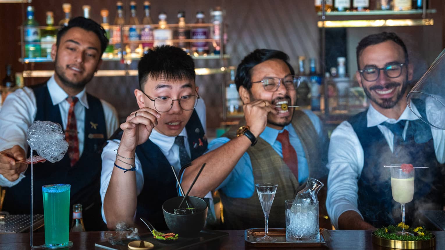 Four bartenders prepare drinks for guests