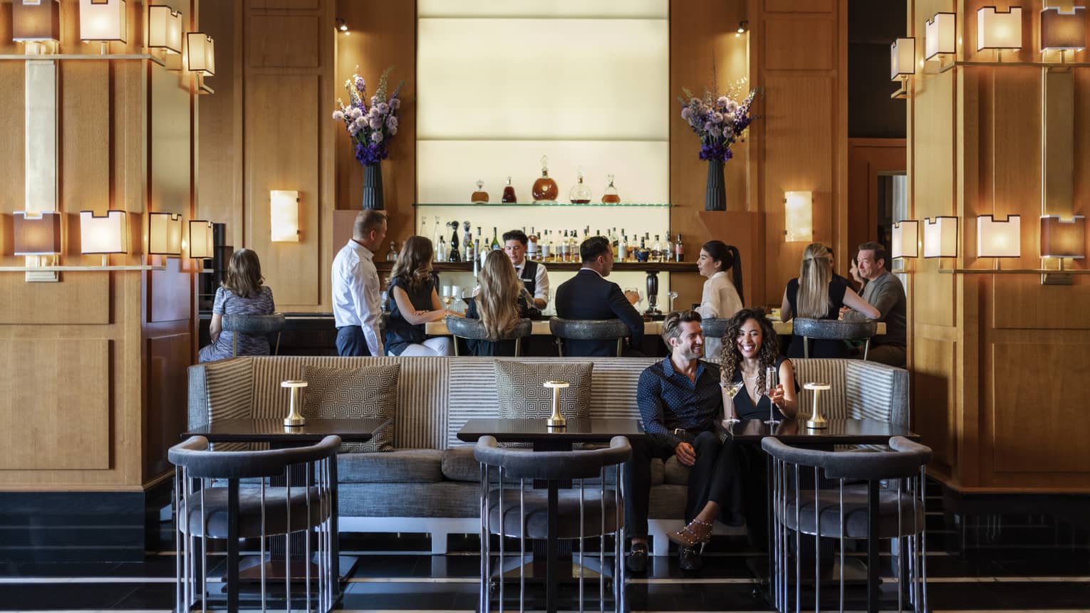 People sitting at a bar and booth in a dining outlet.