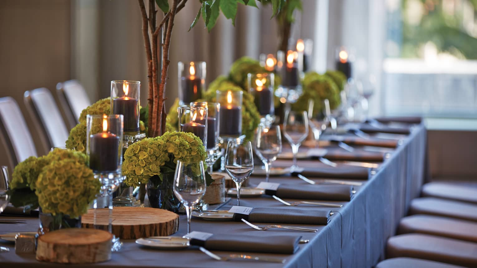 Black pillar candles in votives, green flowers, wine glasses along banquet table