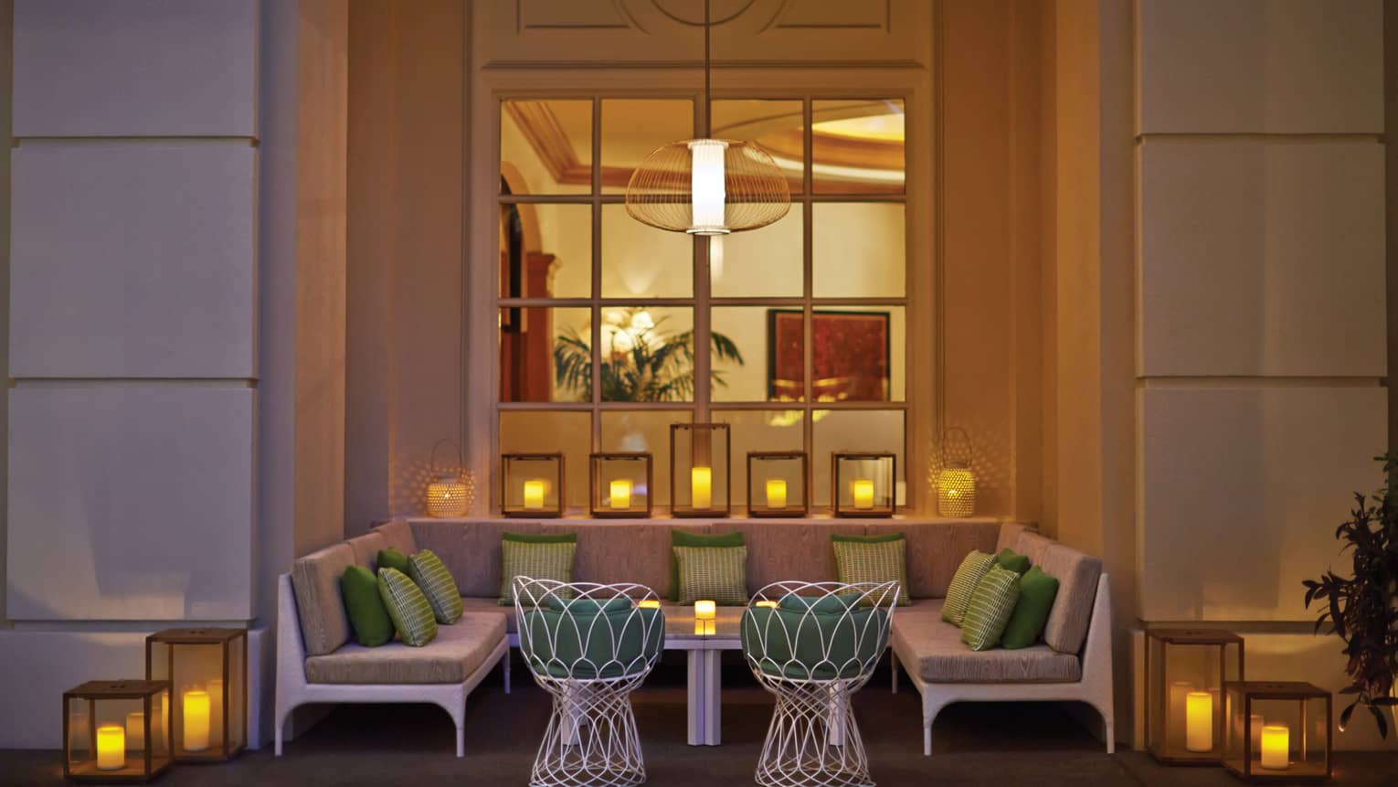 A large booth in a building surrounded by candles and near a large window.