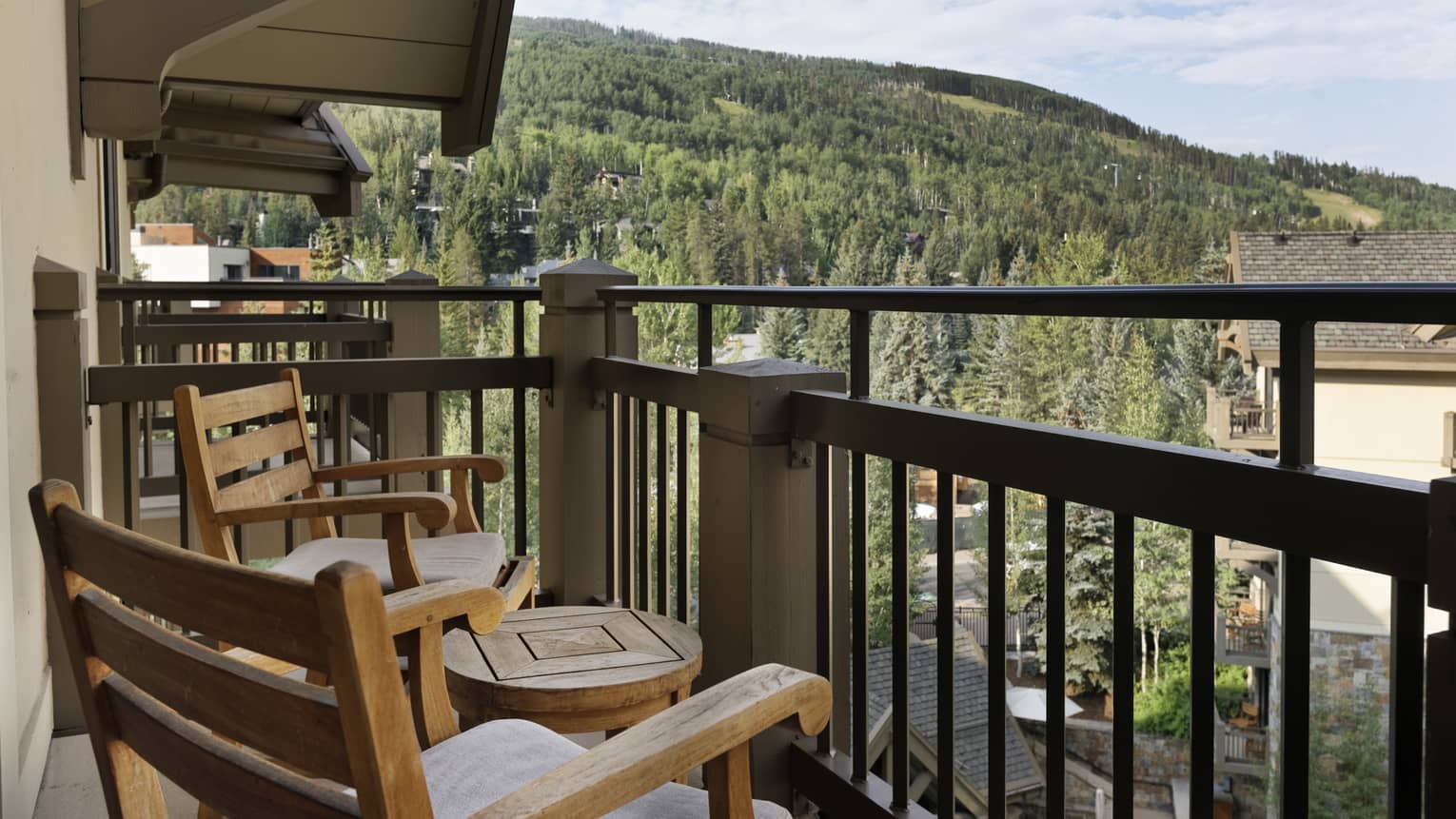 Balcony with portico, two wooden rocking chairs and small round table, mountain views
