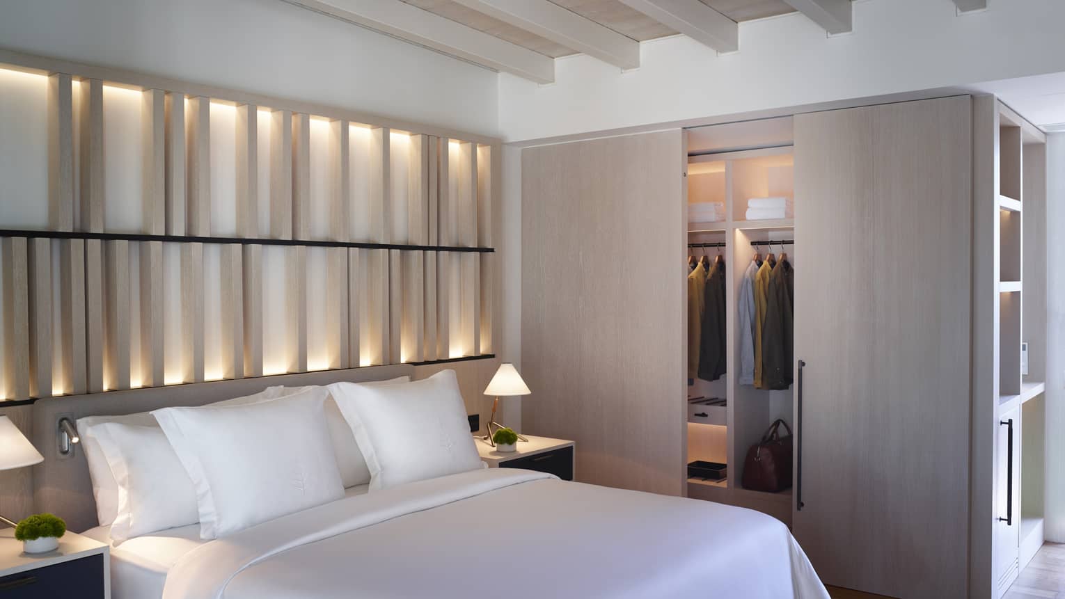 Bungalow Sea View with white king bed, backlit wall, closet with sliding wooden doors, exposed rafter ceiling, ceiling fan