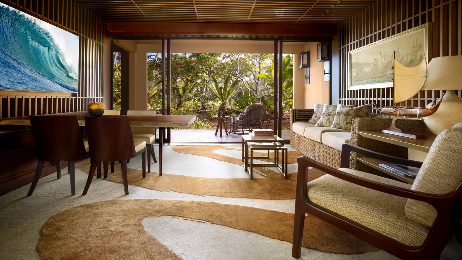 Ohana Garden-View Suite teak-panelled walls, wave screen over wood dining table, sofa, swirl-patterned carpet
