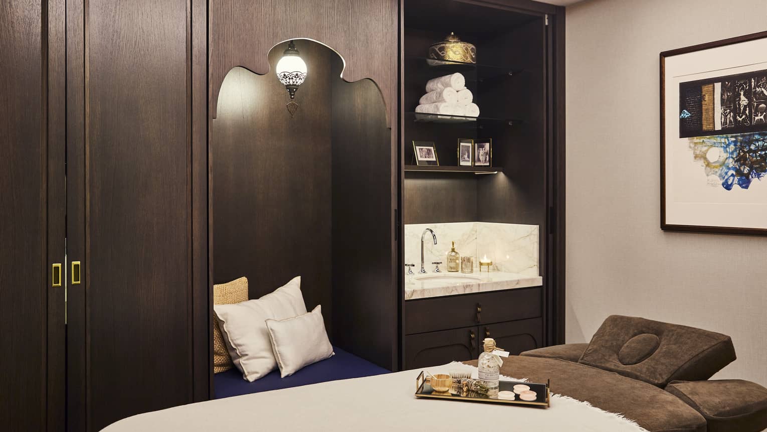 Kuma Spa treatment bed with tray with oils next to large wood cabinet with pillows and sink