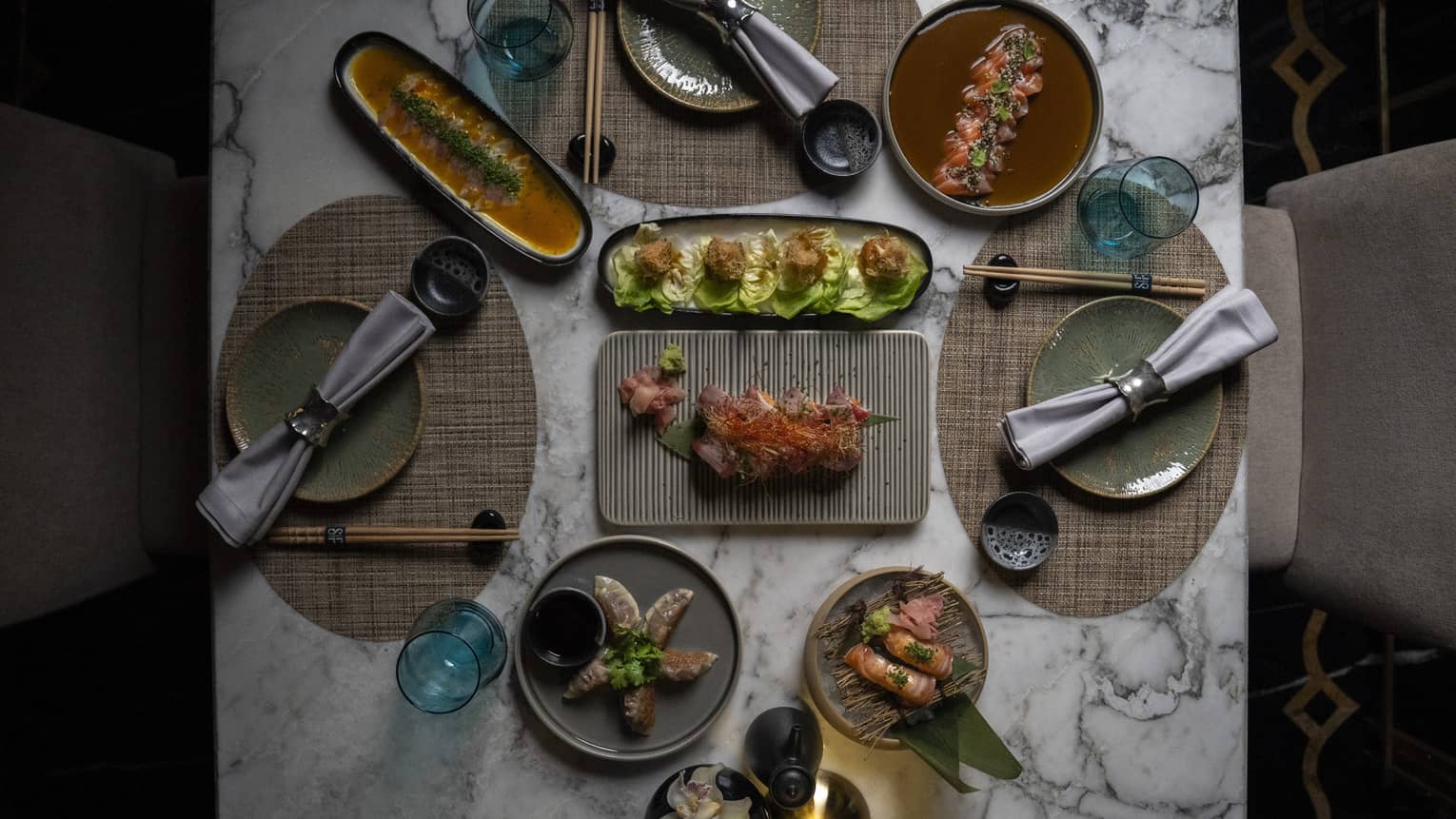 Overhead view of Jappanese Nikkei cuisine on a white marble table set for three
