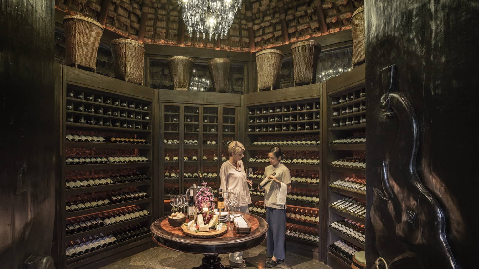 Two people examine wine bottles in Camp Wine Cellar