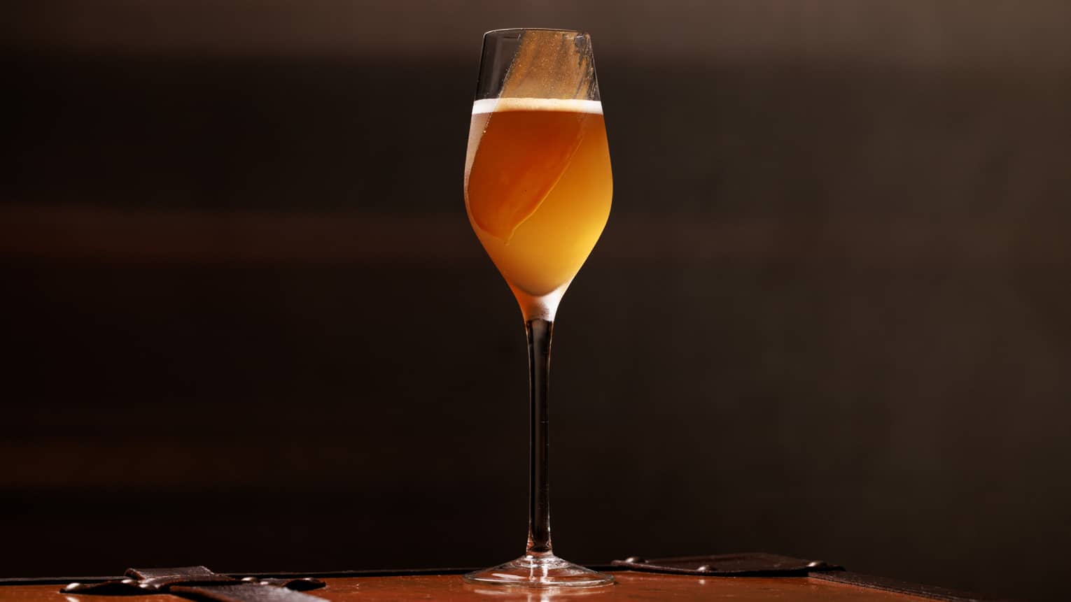 Orange-yellow-coloured cocktail in a flute