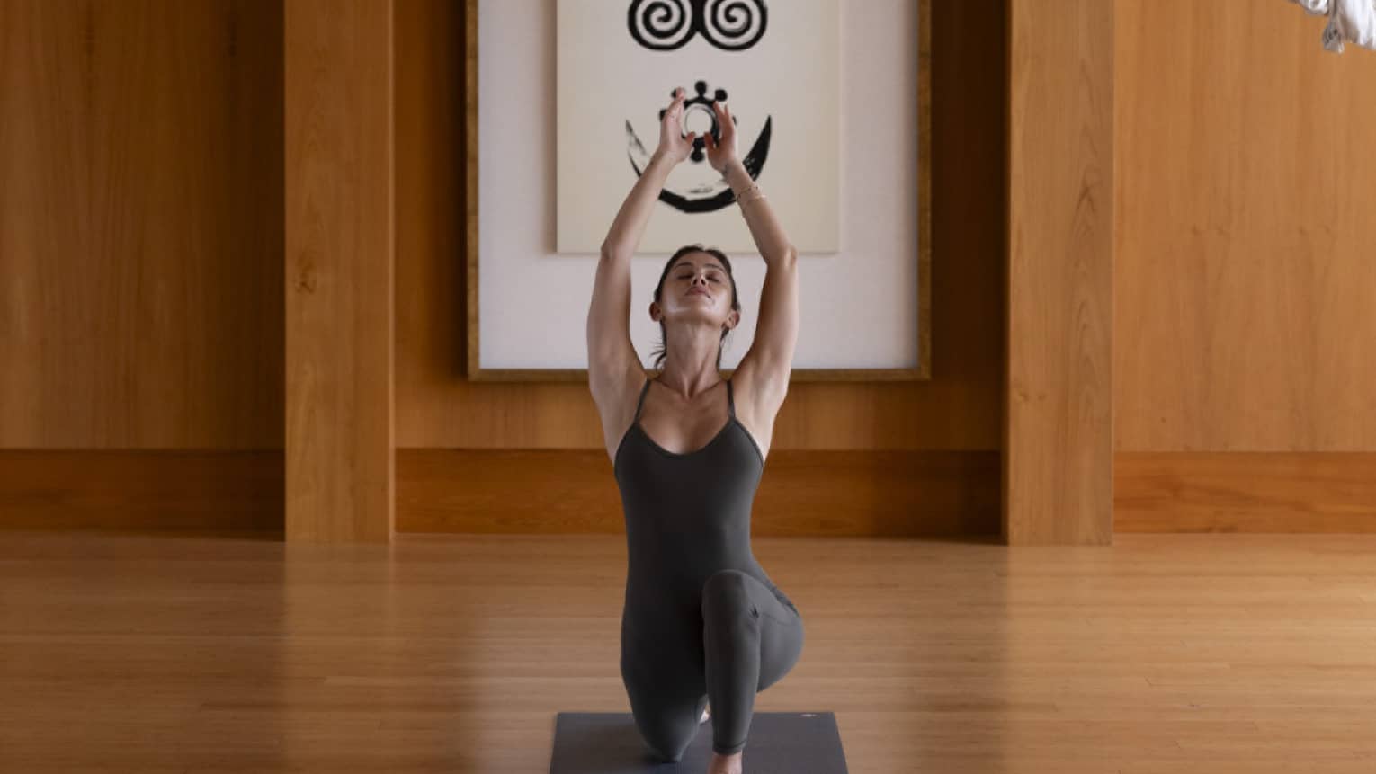 Woman practises yoga in indoor studio with wooden floors and walls