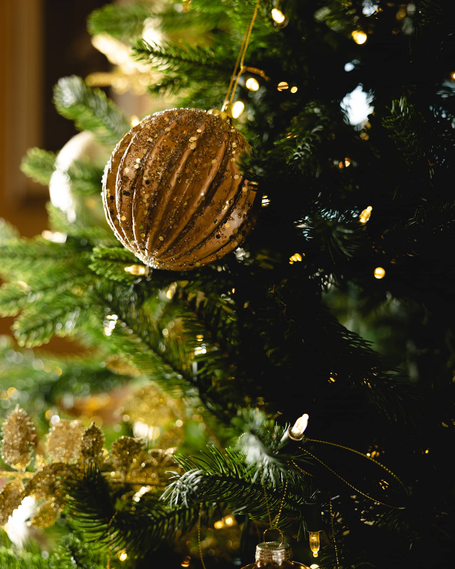 Gold ornament hangs on a Christmas tree