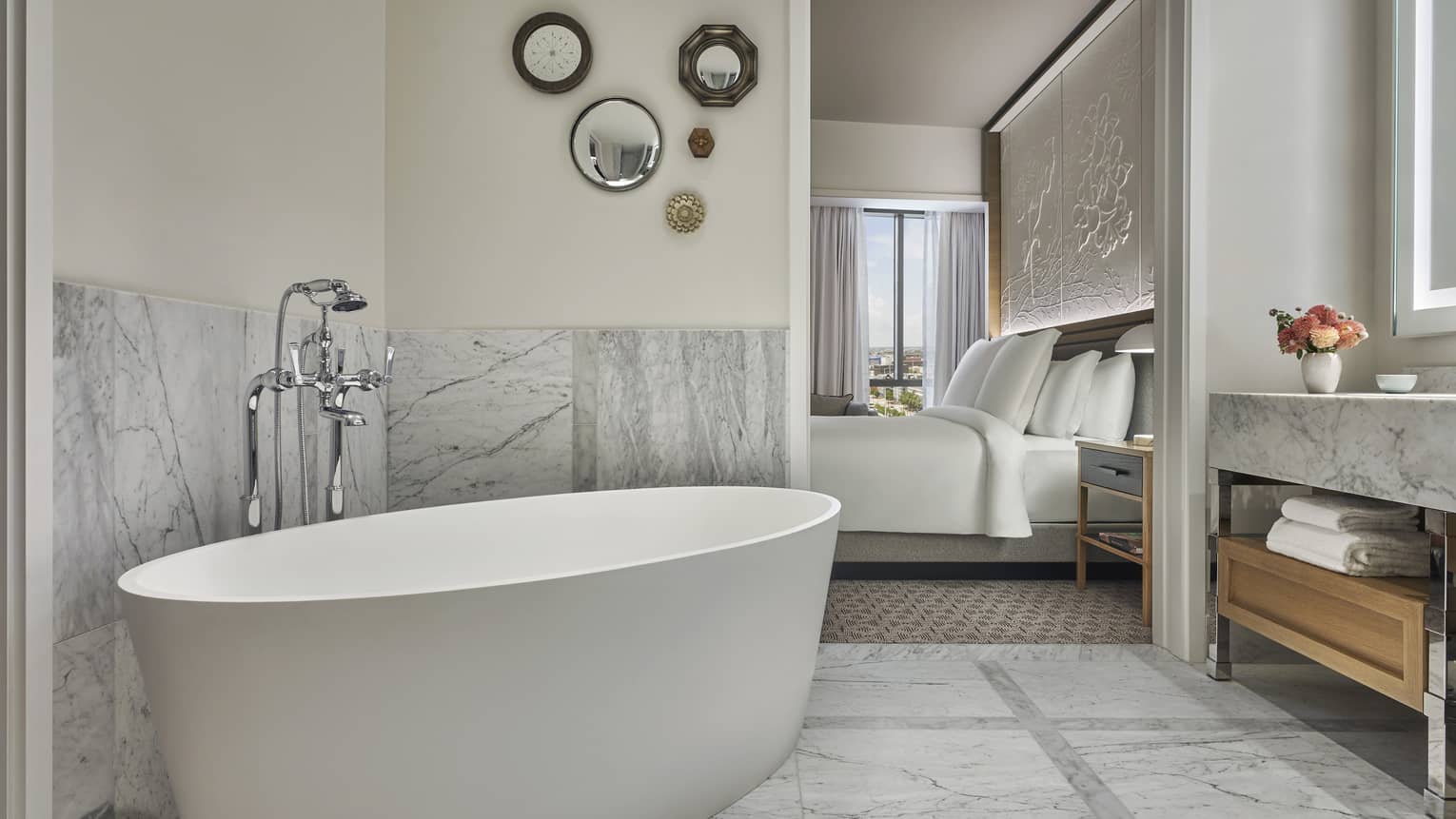 Premier King bathroom with marble counters and floors, large soaking tub, lighted mirror, wooden under-sink storage with towels