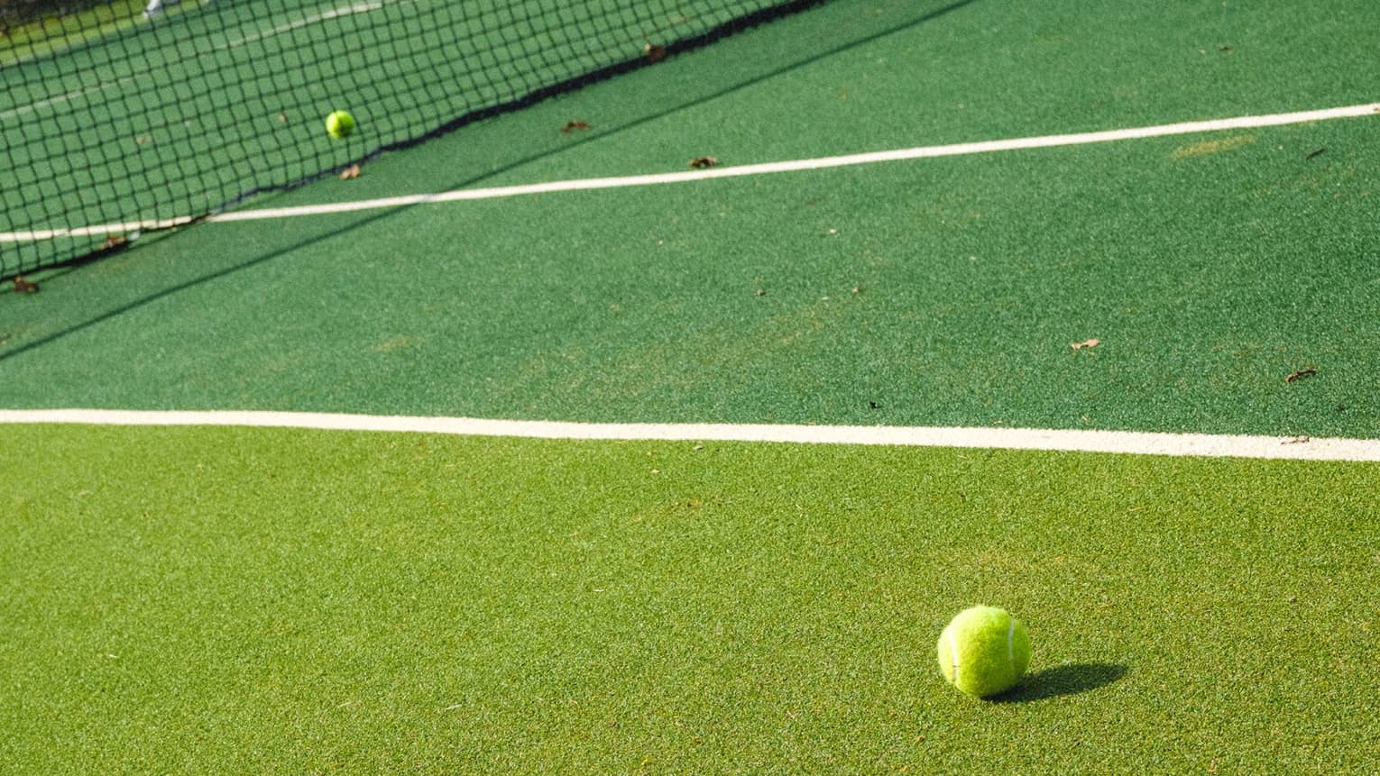 Tennis racquet and two tennis balls on two-tone tennis court