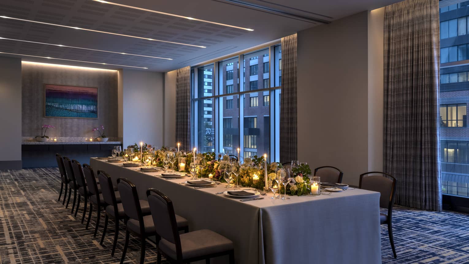 A long table with candles and flowers in a dimly lit room.
