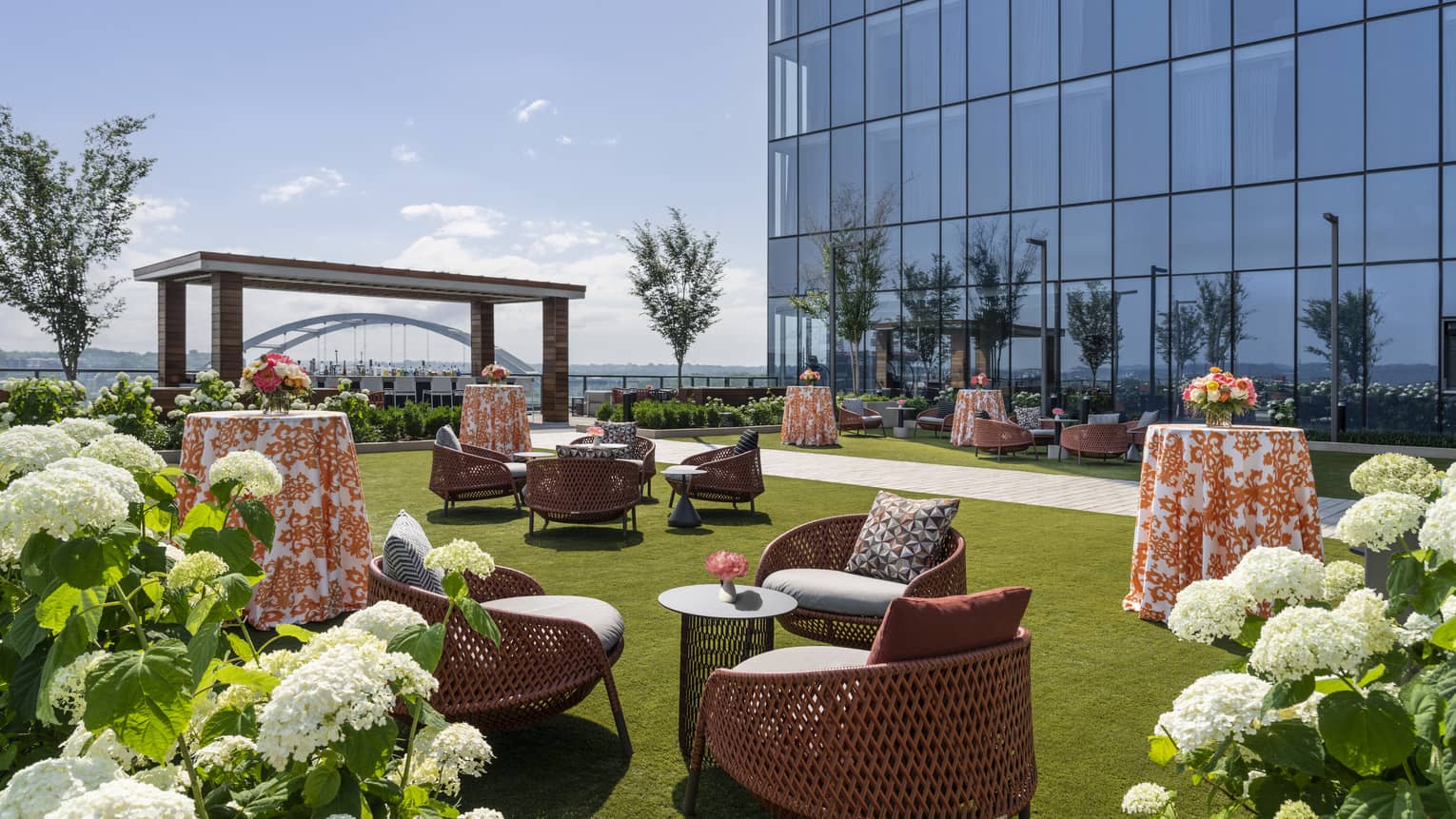 Lawn with chairs and tables and plants with white flowers.
