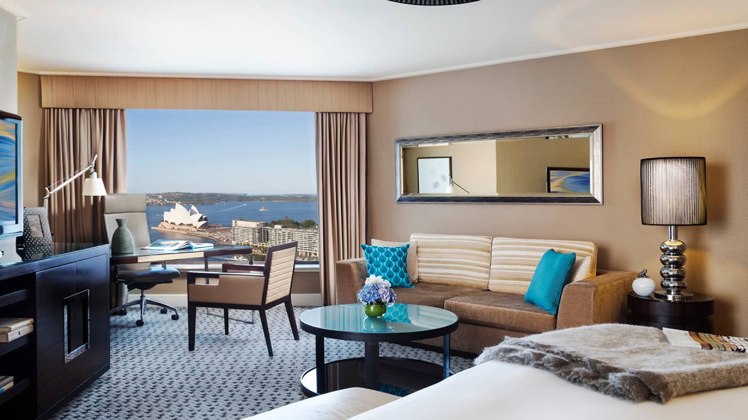 Premier Full Harbour Room, edge of bed, table with flowers, velvet sofa and blue pillows
