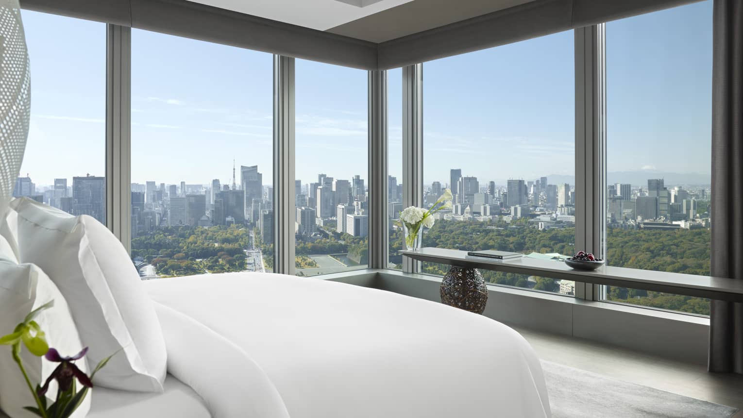 Panoramic hotel room with a king bed, side table with flowers and long console table with orchids
