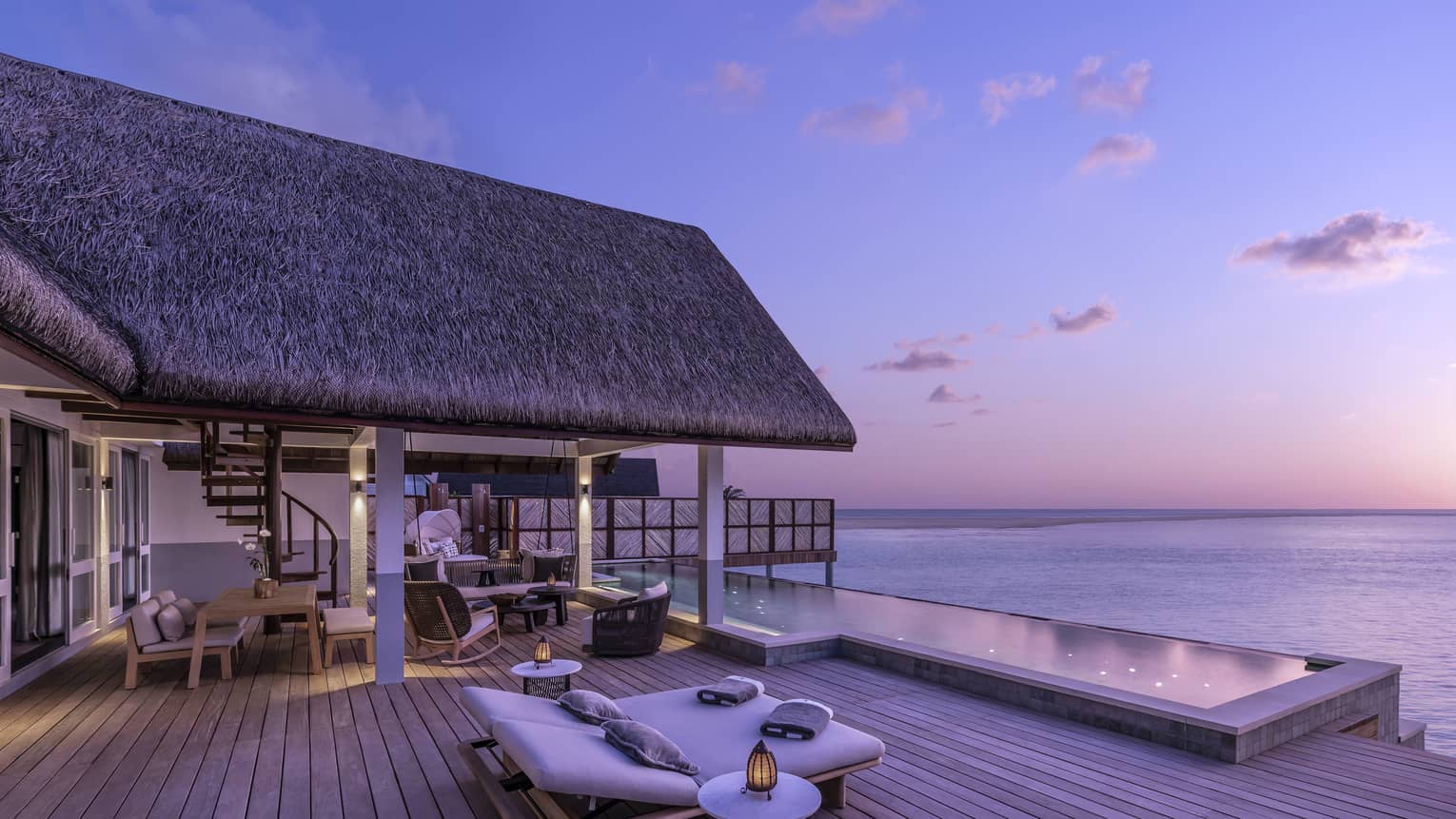 Luxurious overwater bungalow with an expansive wooden deck and infinity pool