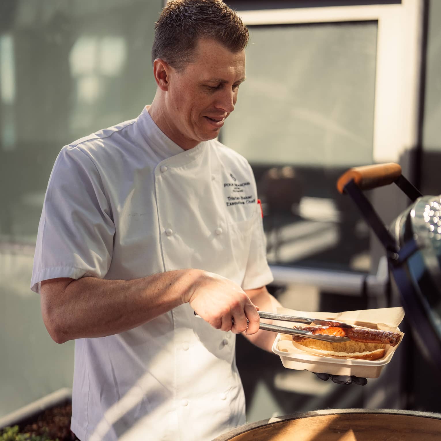 A chef using tongs to place food on a grill