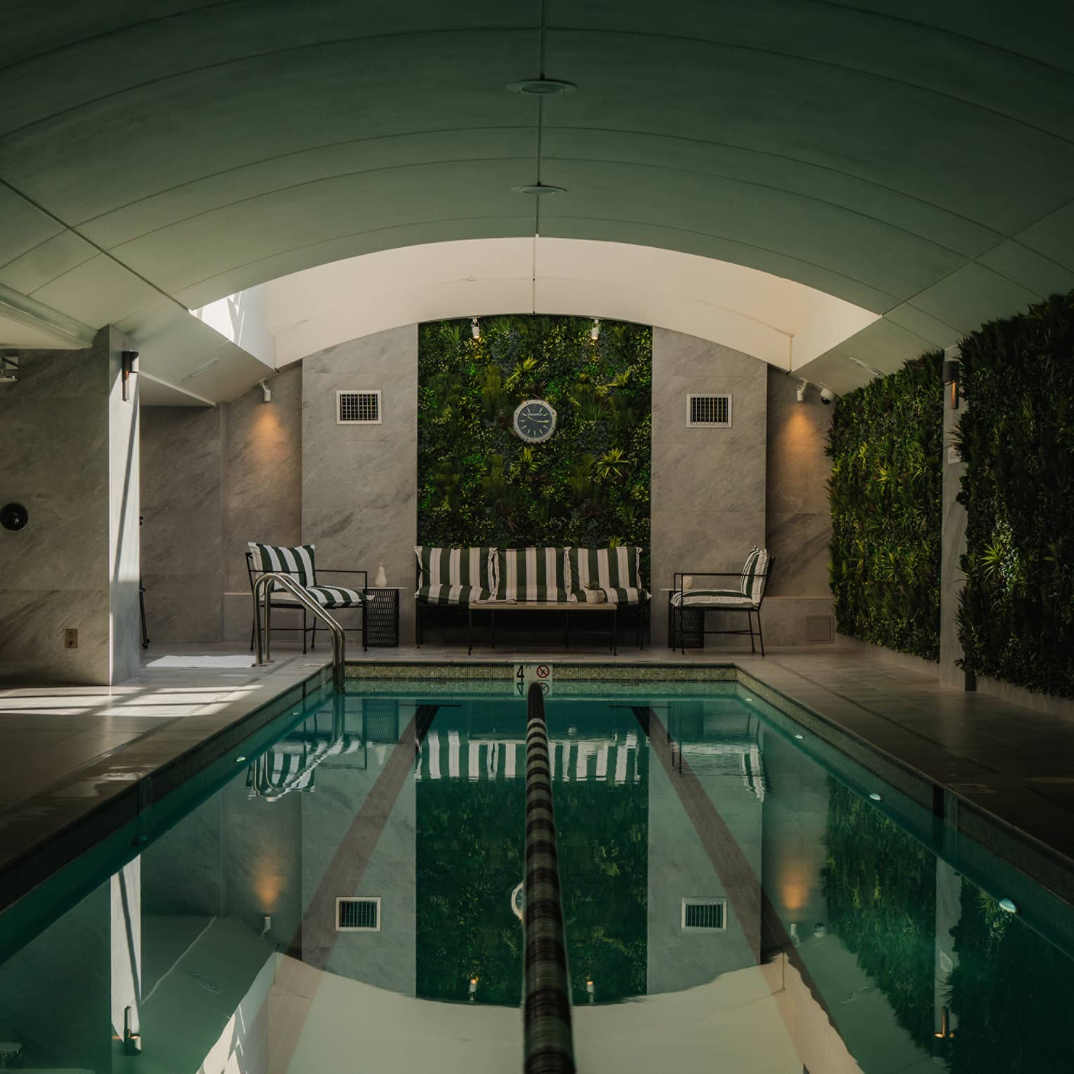An indoor pool with a seating area and a vaulted ceiling