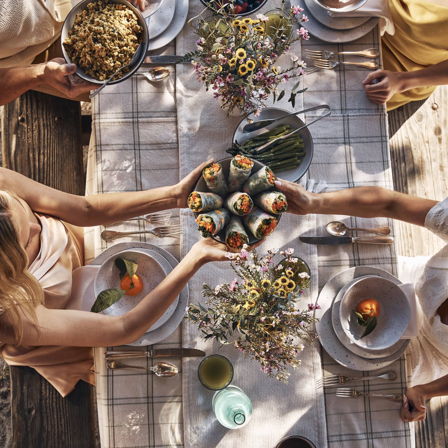 Guests sitting around a table and passing bowls of food.