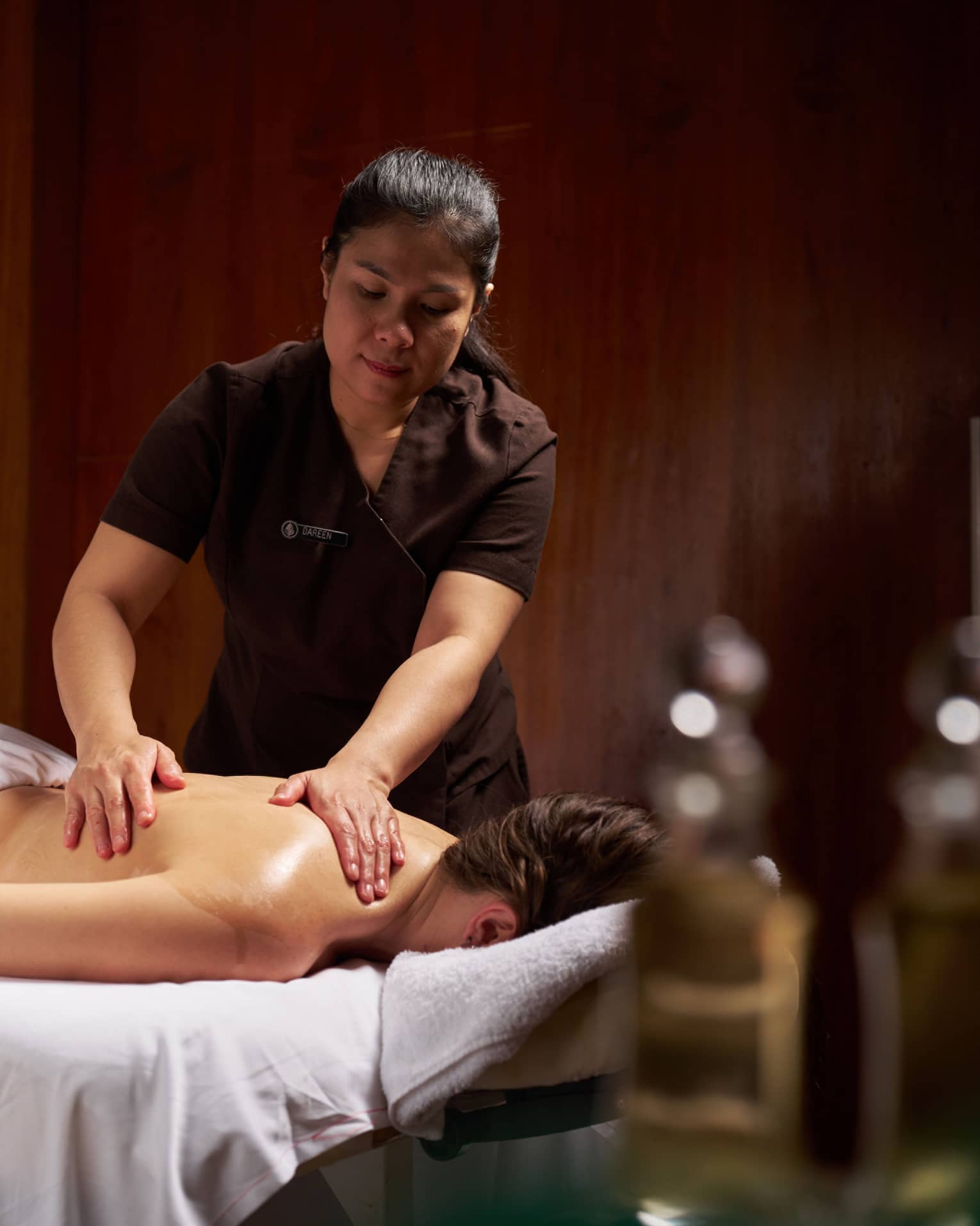 Masseuse performs treatment on female guest lying face down on massage table