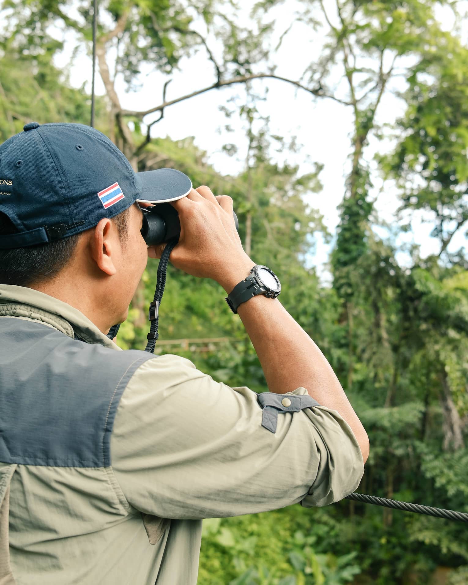 A man looks for birds through binoculars in jungle