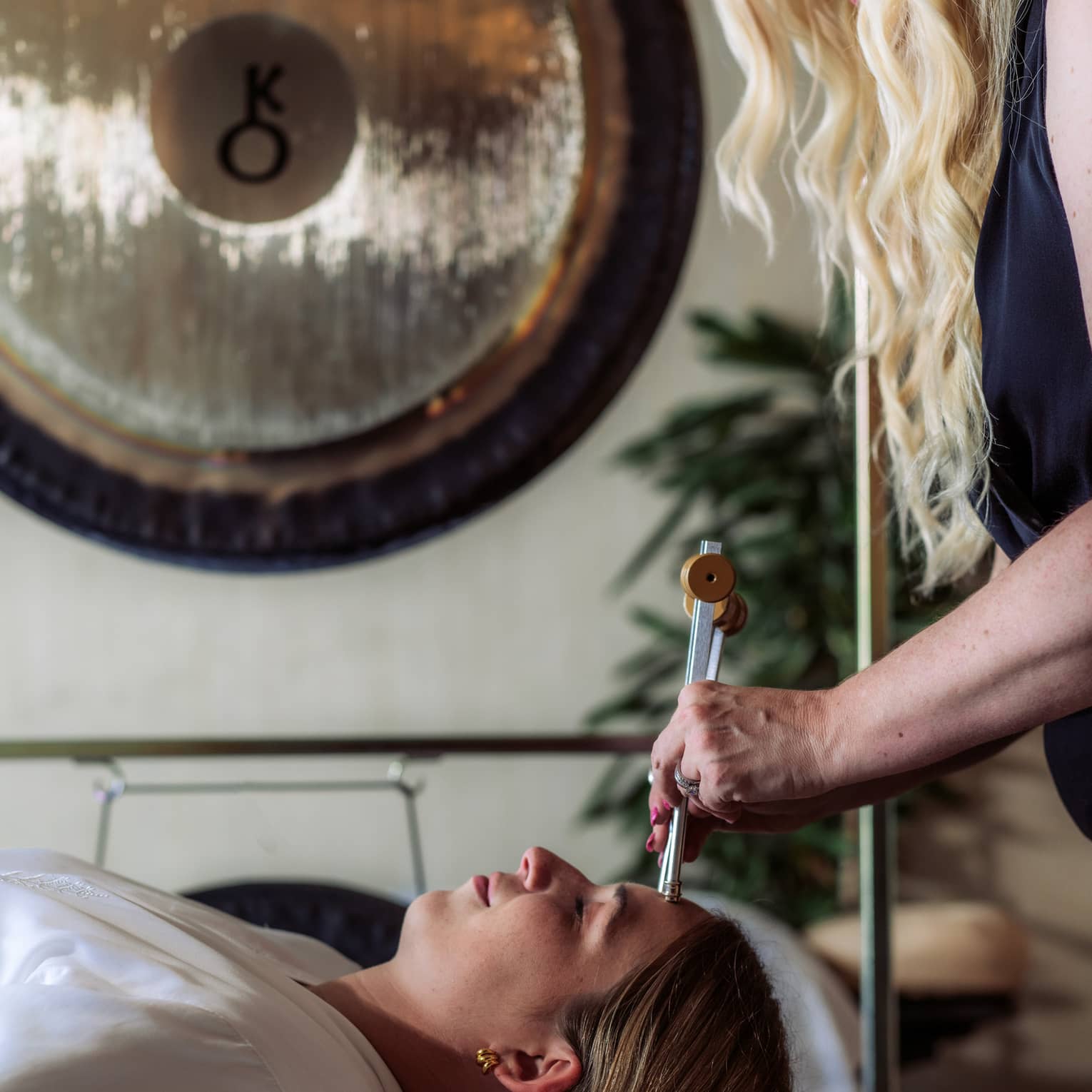 A woman receiving a sound healing treatment at a spa.