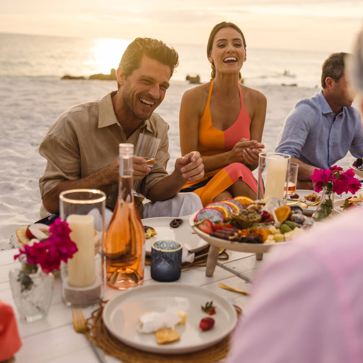 Guests sitting at a picnic table on the beach near the ocean