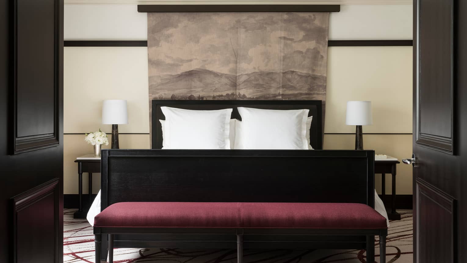 Open black French doors revealing Executive Suite bed, burgundy velvet bench at foot