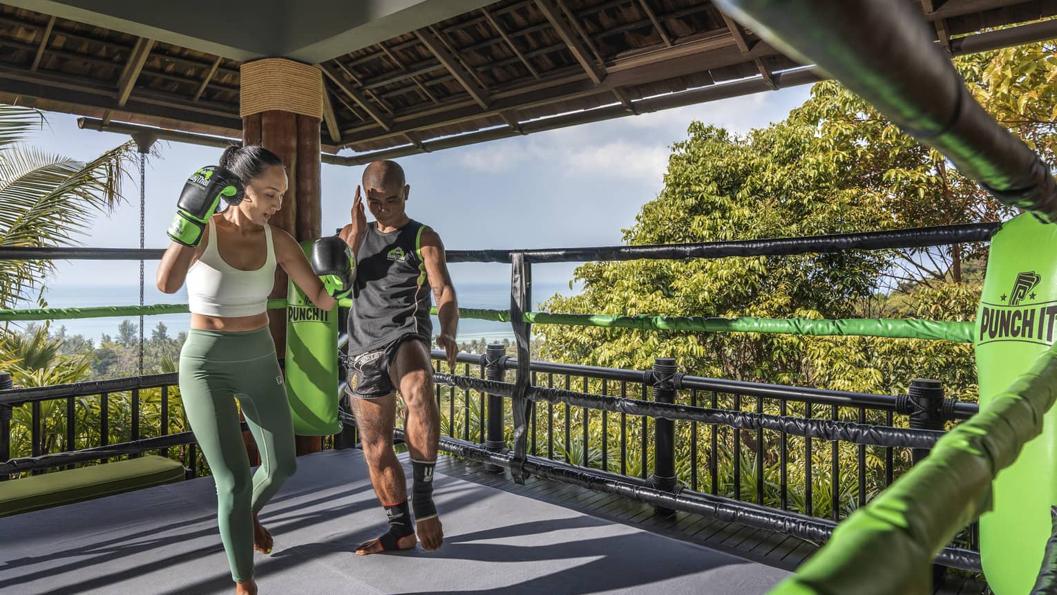Muay Thai trainer teaches woman in outdoor ring