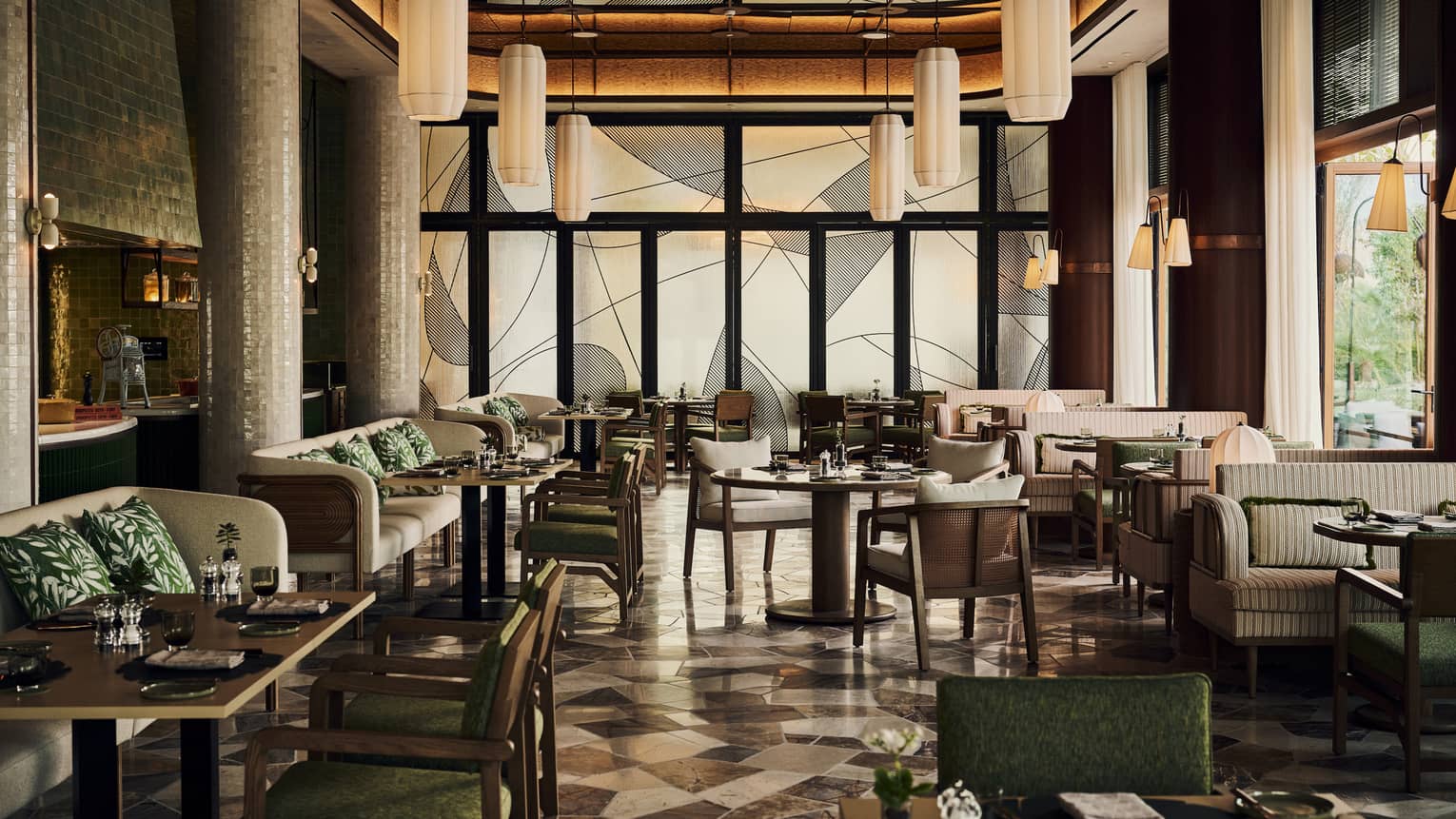 Interior of modern restaurant with black and white tiled floors, booths and chairs, and hanging lanterns
