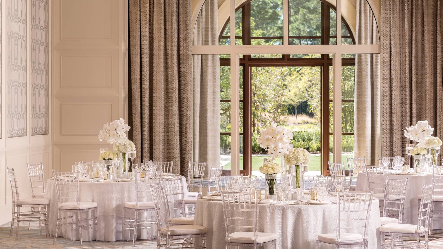 The Palm Ballroom with elegant white banquet tables under large, sunny arched window