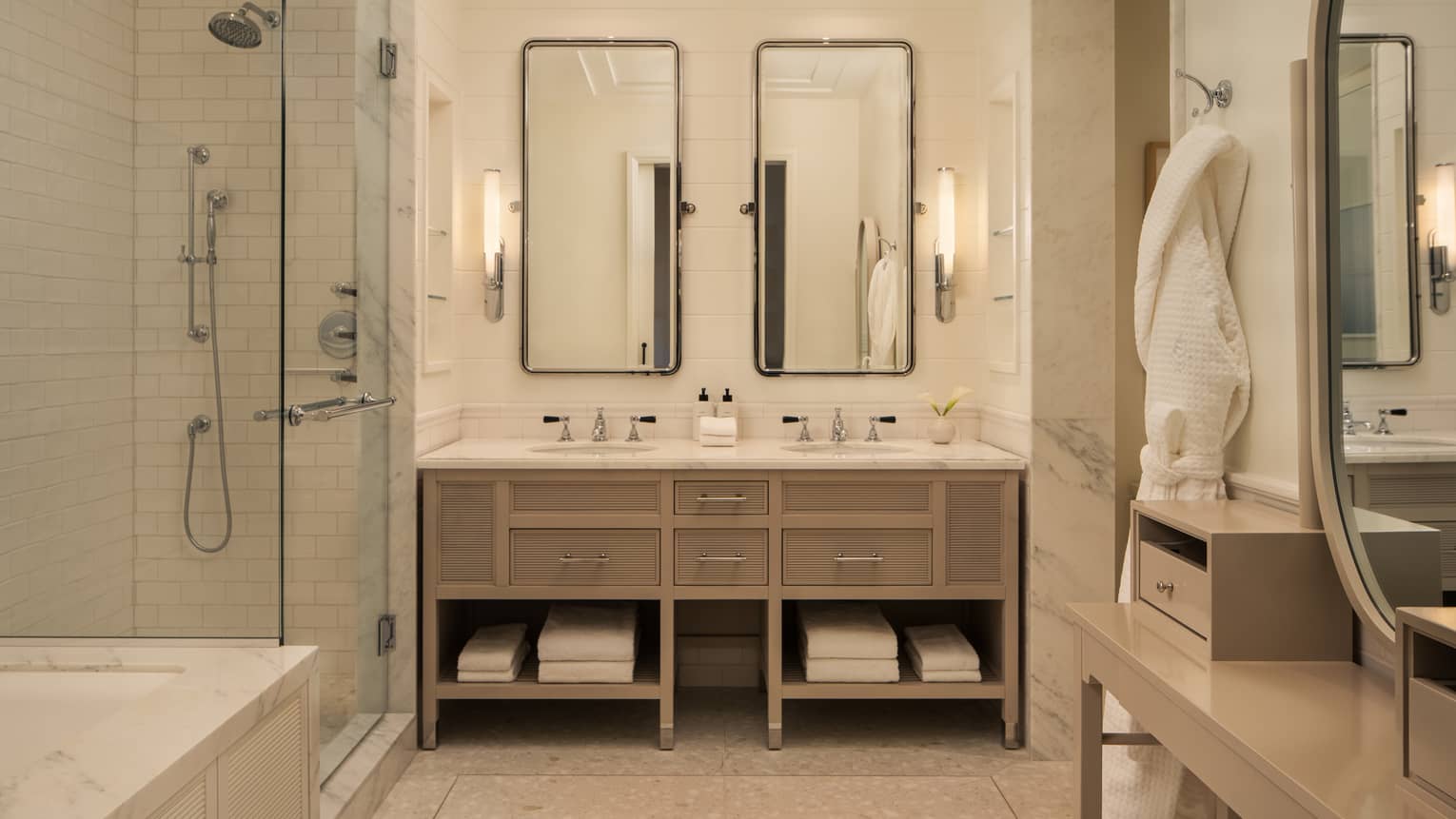 Luxury hotel bathroom with double vanity, glass-enclosed shower and bath tub