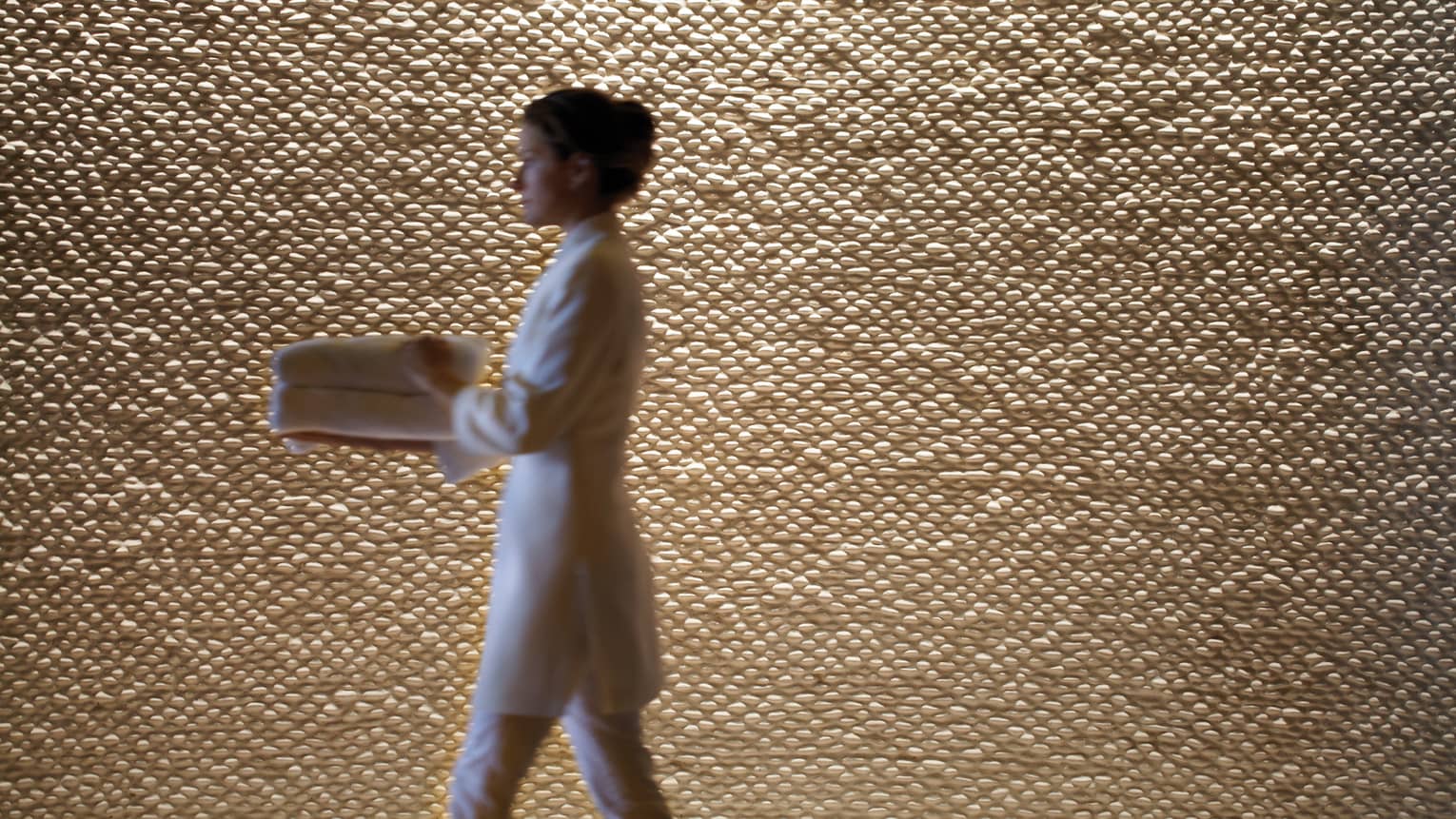 A woman in a spa robe walking by a wall.