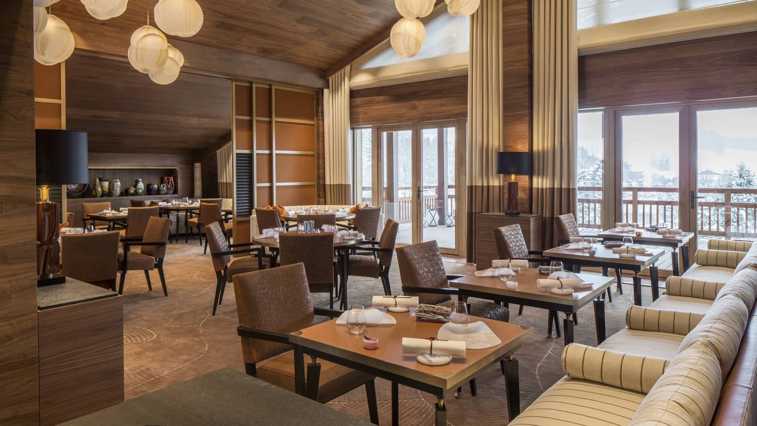 Tables, brown leather chairs, striped banquettes under modern lights in Le 1929 dining room