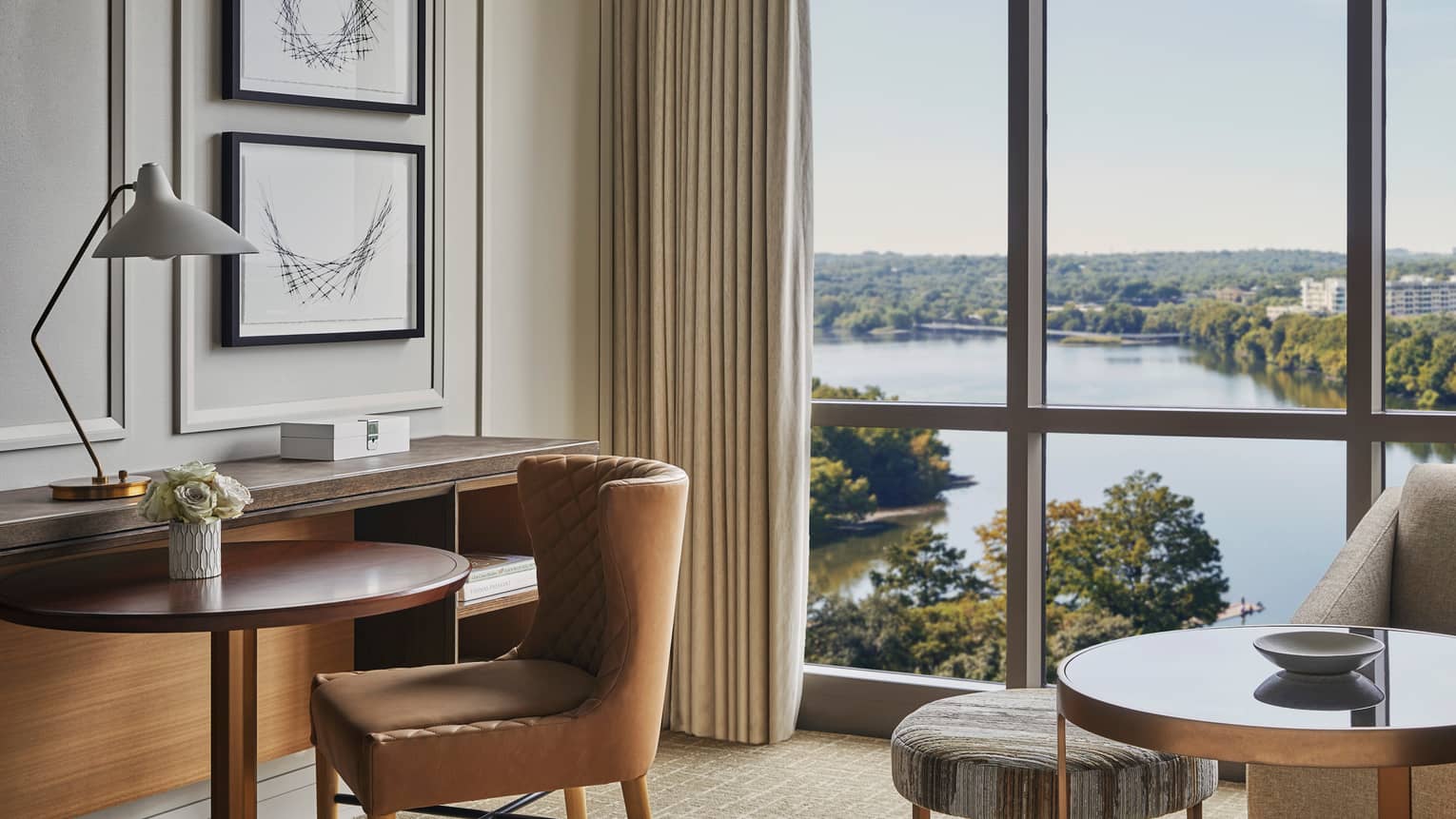 Leather chair by small hotel dining table, floor-to-ceiling windows, Lady Bird Lake views