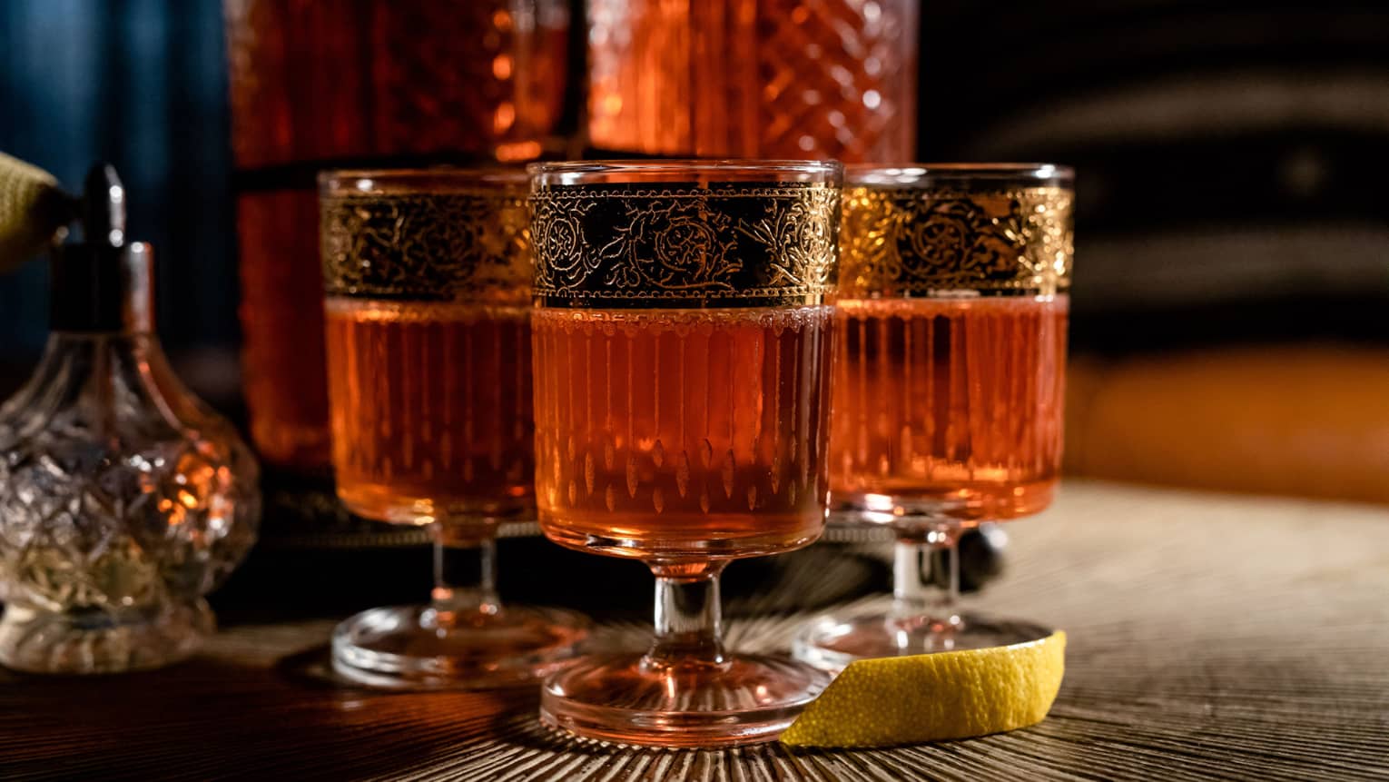 Sazerac Flight signature drink at Bandista, in cylindrical glass with gold trim, lemon peel garnish