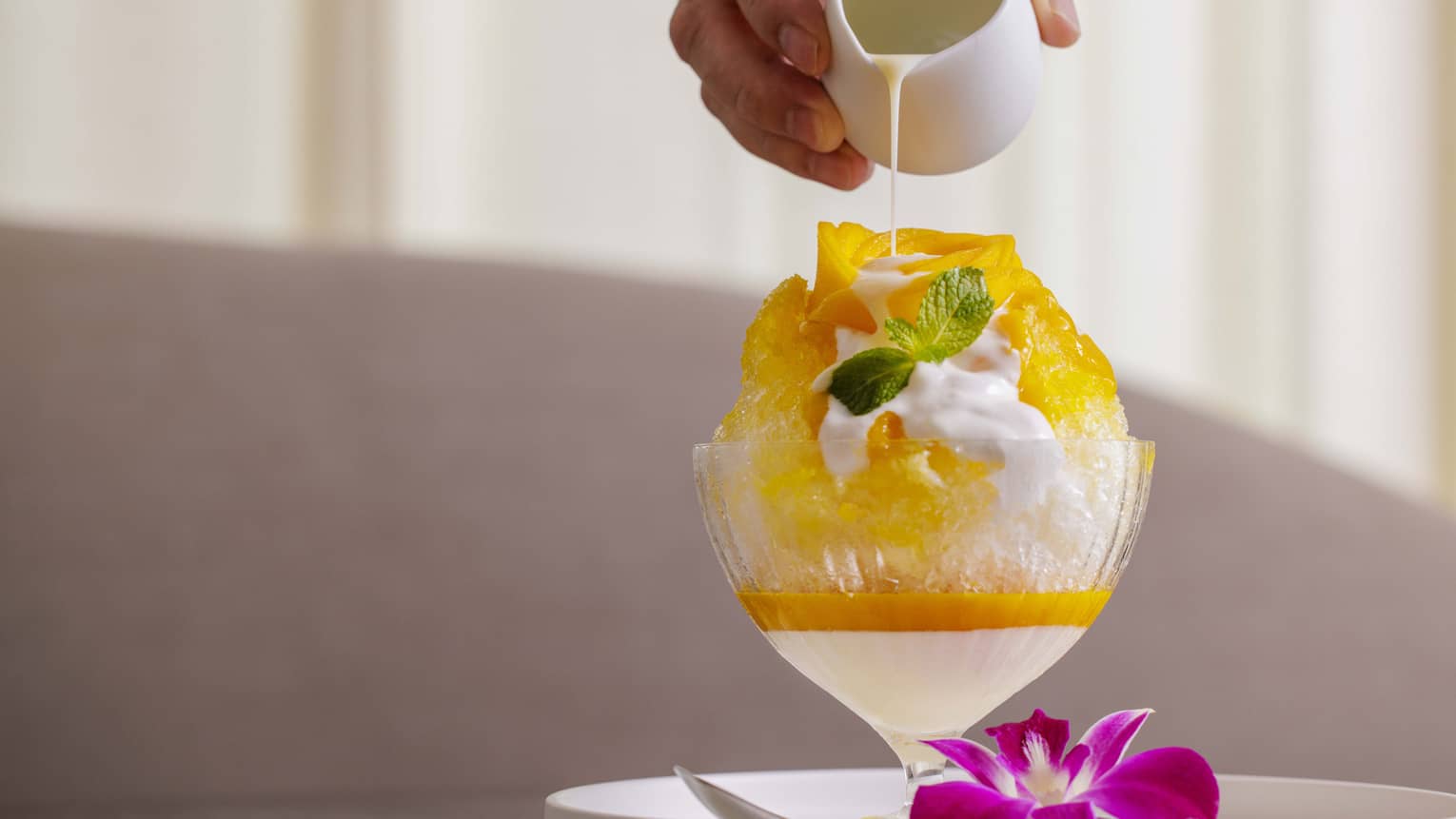 Shaved ice in a glass with fruit pur�e being poured on top