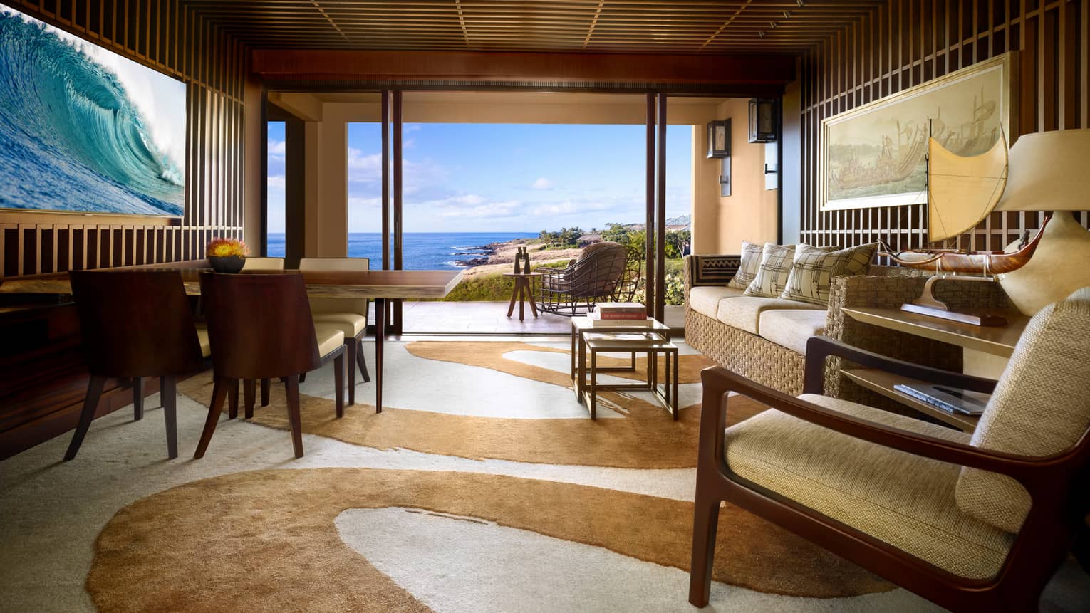 Ohana Ocean-View Suite teak-panelled walls, wave screen over wood dining table, sofa, swirl-patterned carpet