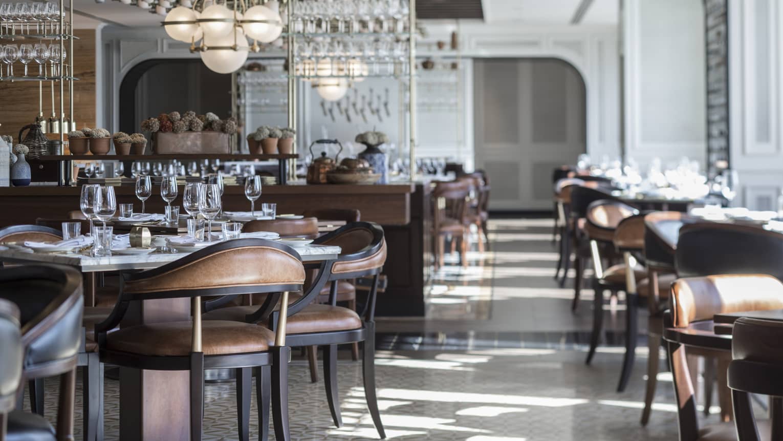Sunny La Capitale dining room with elegant brown leather chairs, tables, white tile, modern globe chandeliers