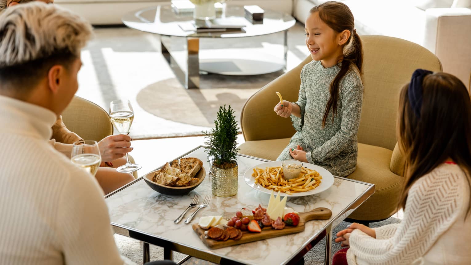 A family of four eating food outside with sunlight shining near them.