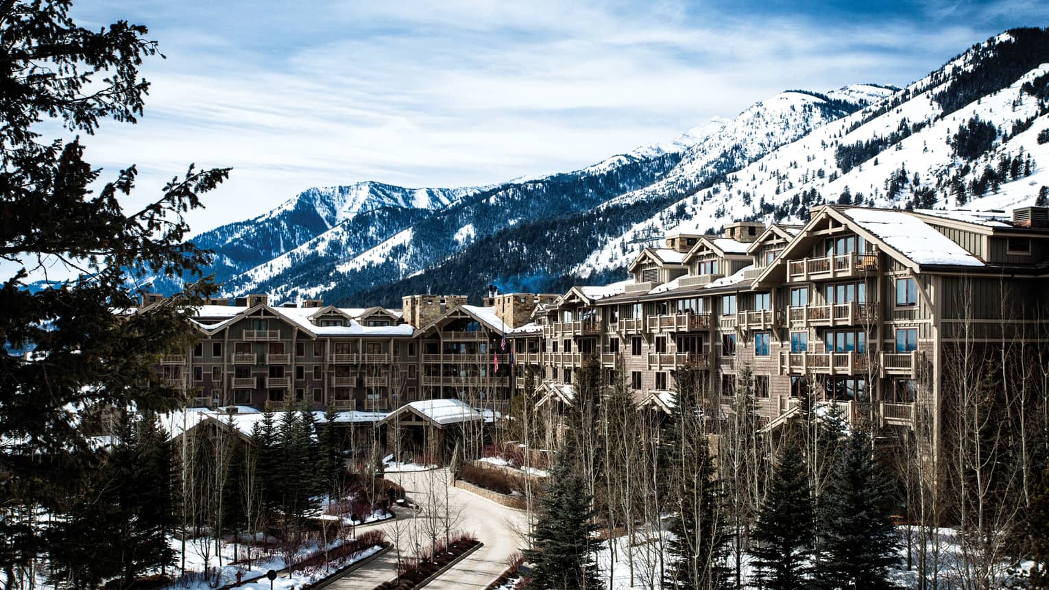 the exterior of the hotel is covered in snow and surrounded by snow capped mountains 