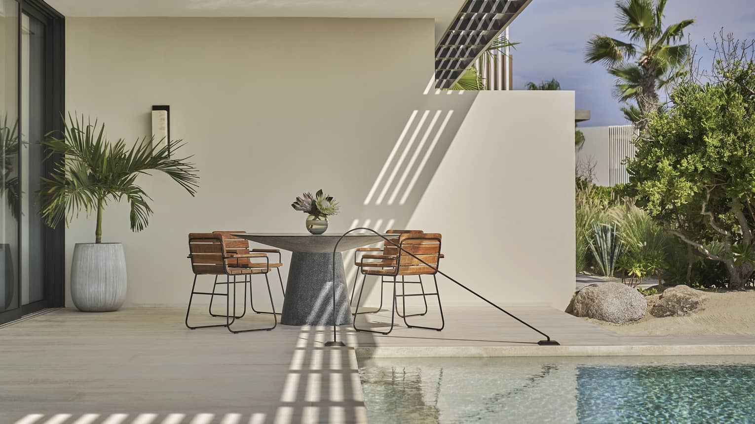 Two Bedroom Sunrise Suite pool with round table, four chairs, potted palm