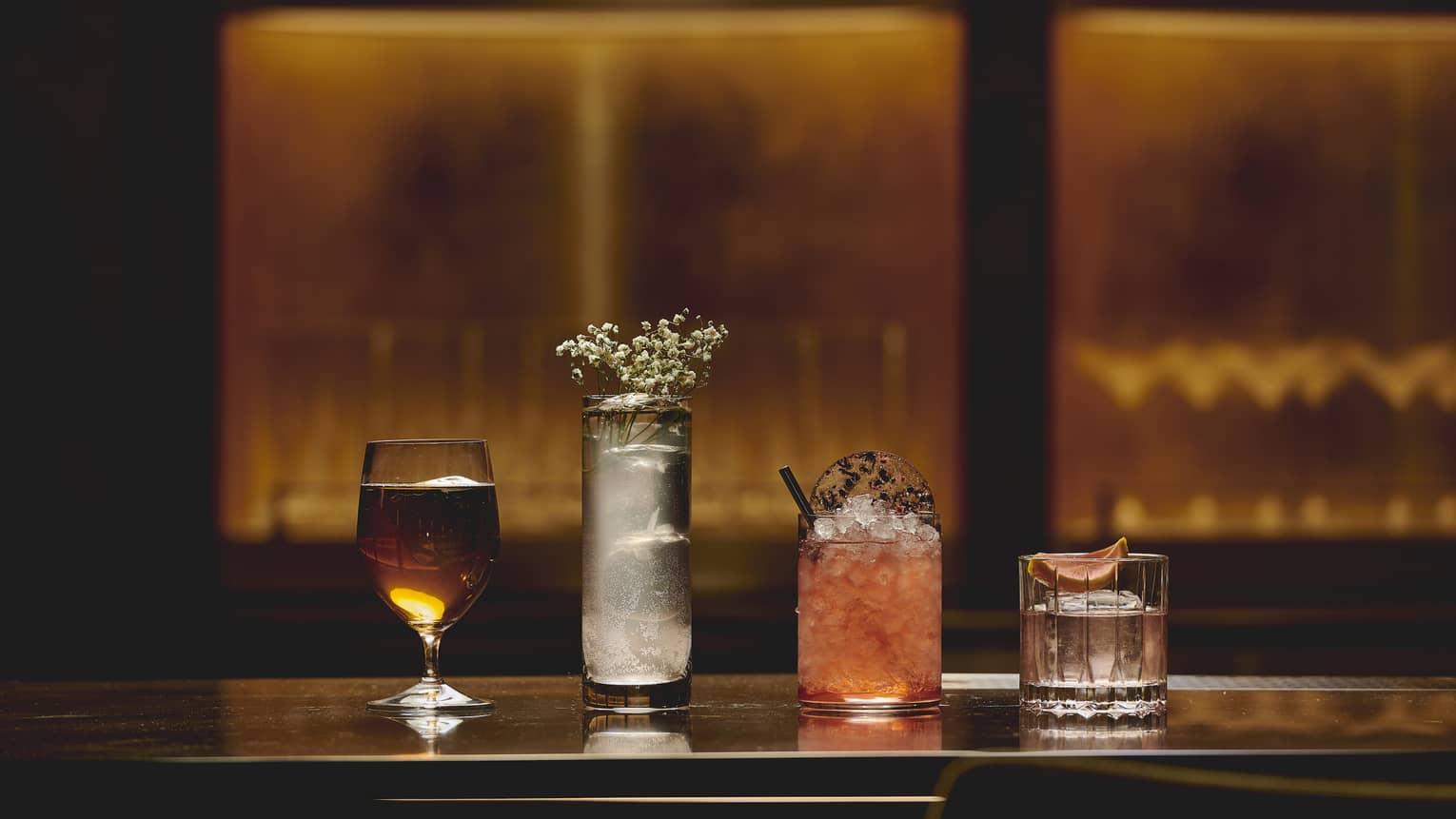 Four different cocktails in a row on the bar