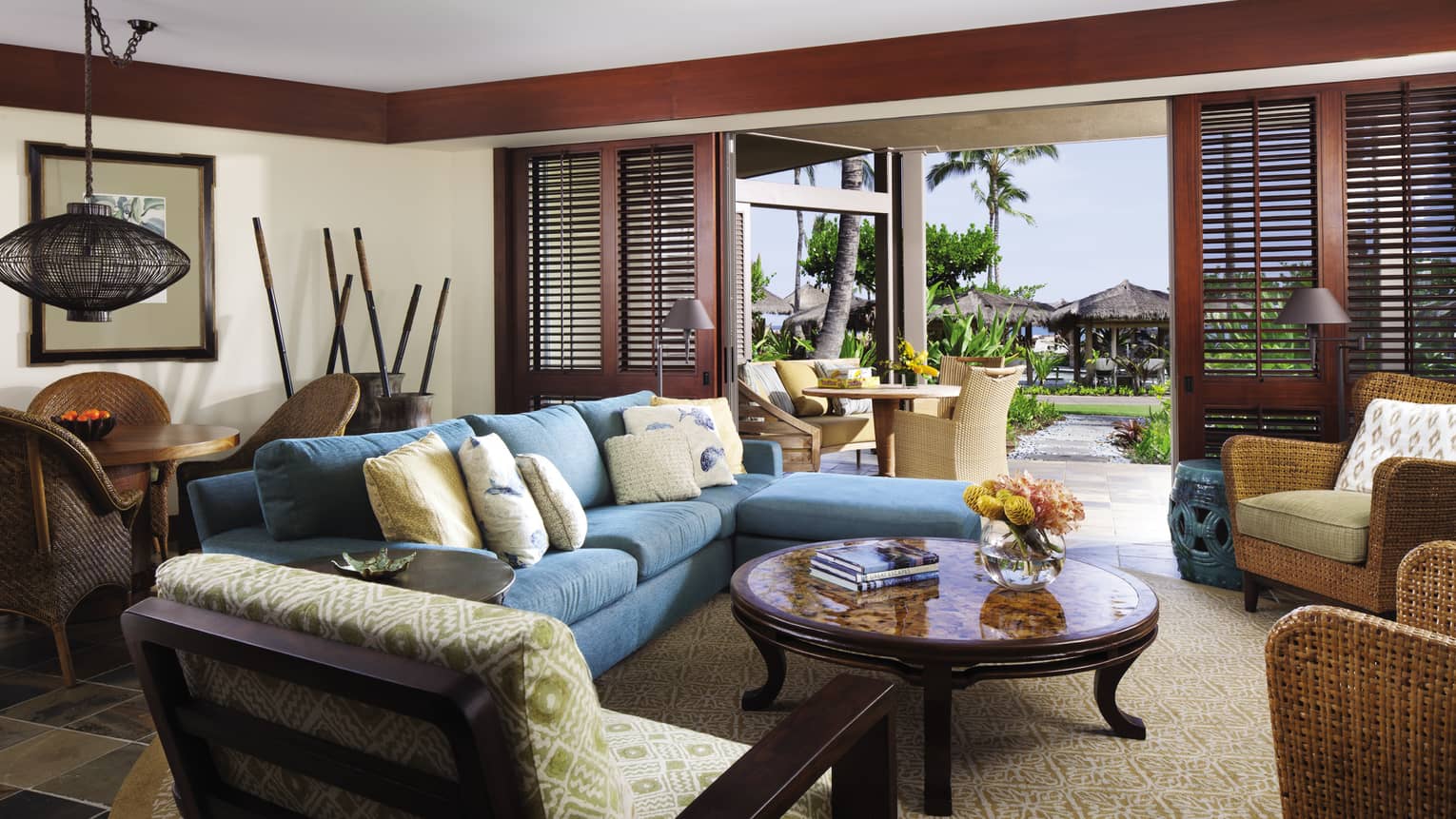 ‘Ohana Suite L-shaped blue sofa, chairs around table, open wood shutters to patio