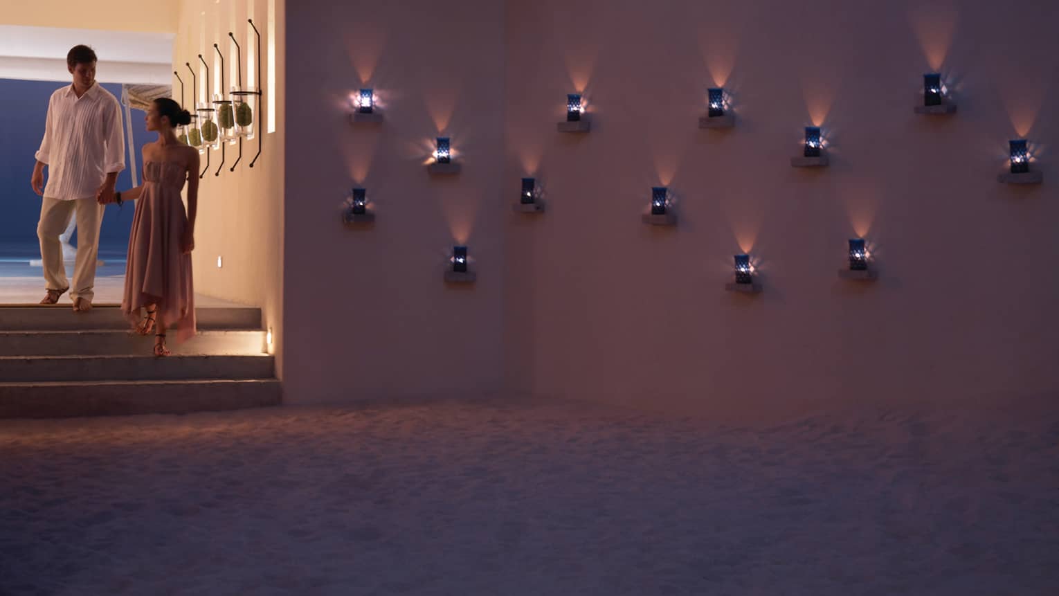 Couples walks down steps to Seabar lounge where small blue lanterns glow along wall
